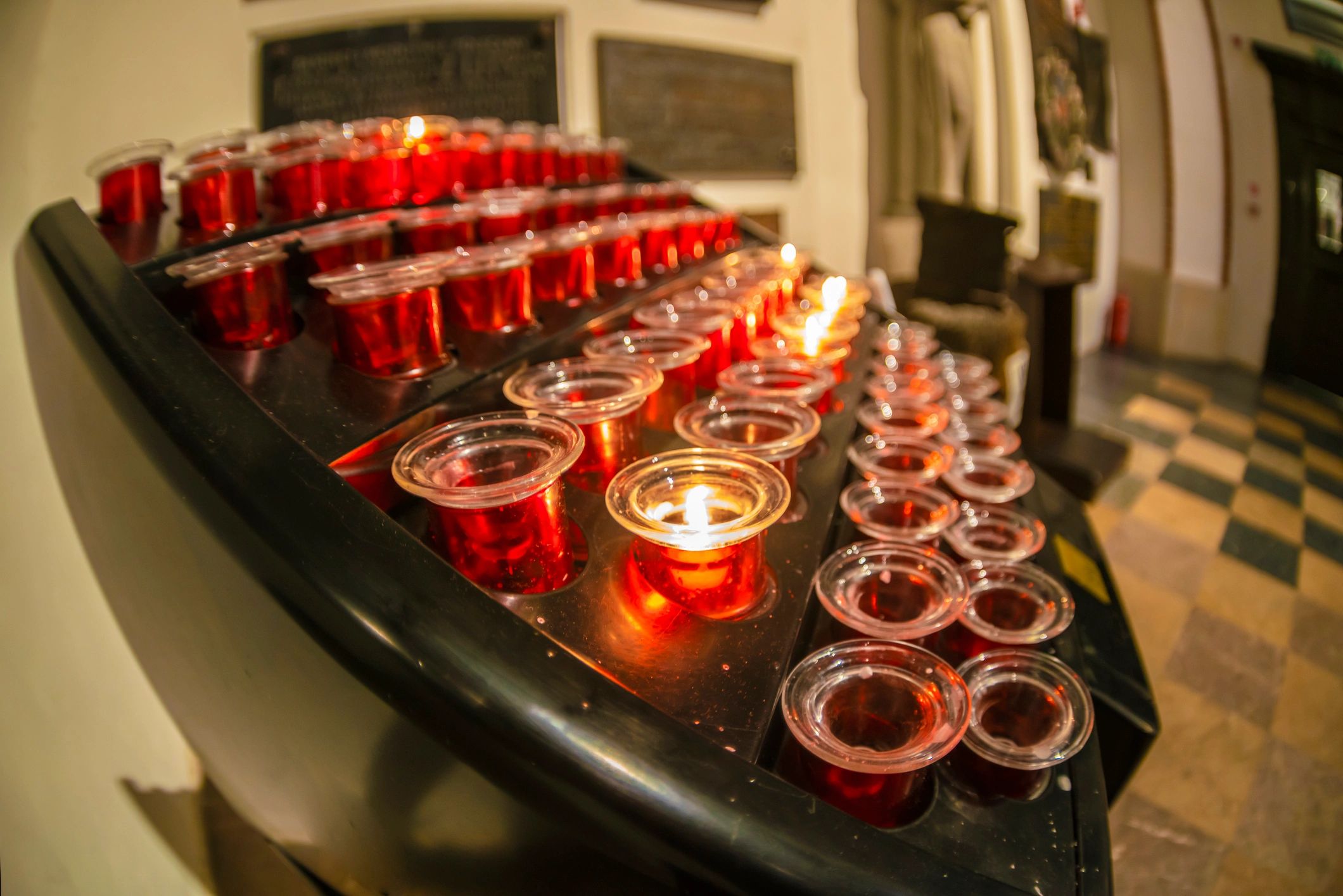 Rows of lit candles before an iconostasis in a church